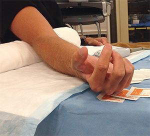 Figure 2. Place an adjustable table under the patient’s arm and a sheet roll directly under the extended elbow.