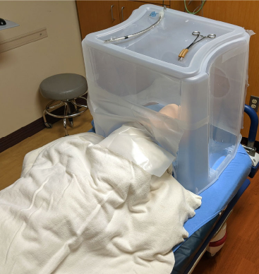 Figure 1 (LEFT): Simulated COVID-19 patient covered by protective intubation box.