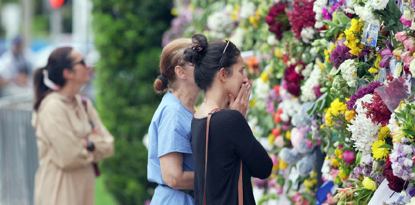 Visitors spend time at the memorial that grew on the fence next to the site.