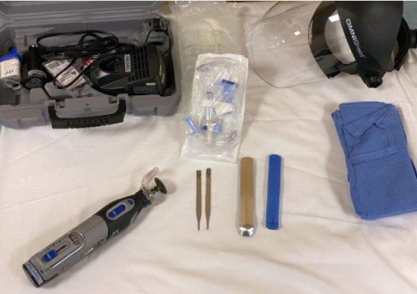 Figure 2: This removal technique requires a rotary grinding tool such as a Dremel, saline drip set for irrigation, face shield to avoid spark injury to the physician, metallic guard such as a foam aluminum splint or forceps split in half, and towels to avoid spark injury to the patient.
